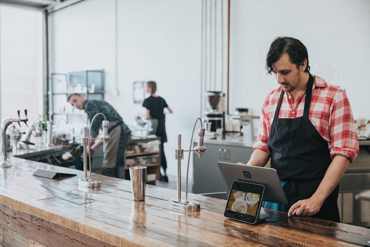 Cafe staff member using a POS tablet at the counter